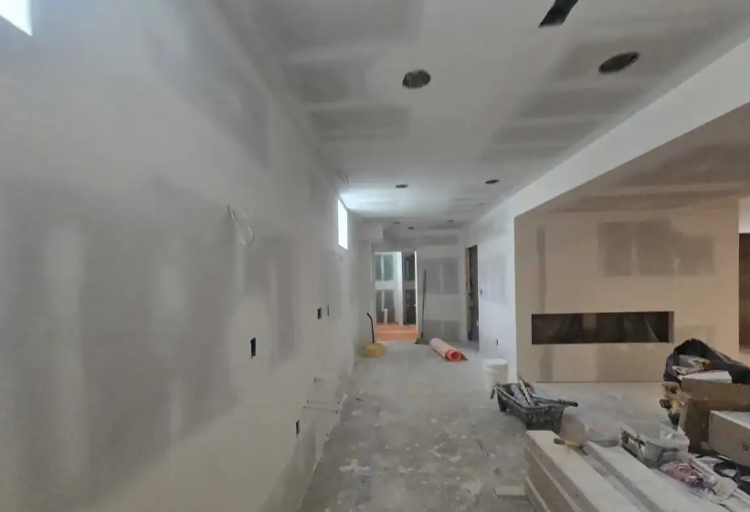 Open concept drywall installation with recessed lighting and fireplace